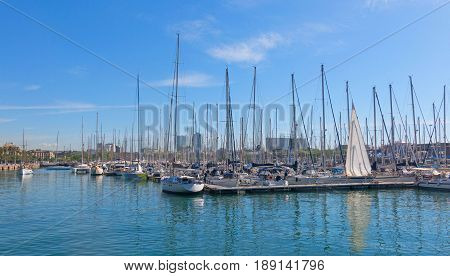 Sailboats moored in the port of barcelona near the Ramblas and the monument of Columbus on May 16 2017 in Barcelona Spain.