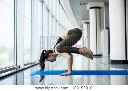 Crane Crow Pose. Woman Yoga Practice Pose Training Concept In Gym Hall With Big Windows