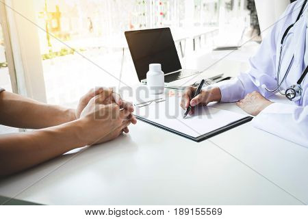Healthcare and Medical concept patient listening intently to a female doctor explaining patient symptoms or asking a question as they discuss paperwork together in a consultation.