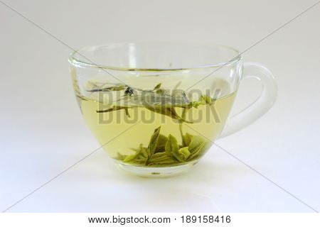 A transparent cup of green tea on a white background