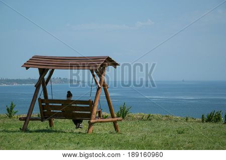 Girl sitting on a swing with a sea view
