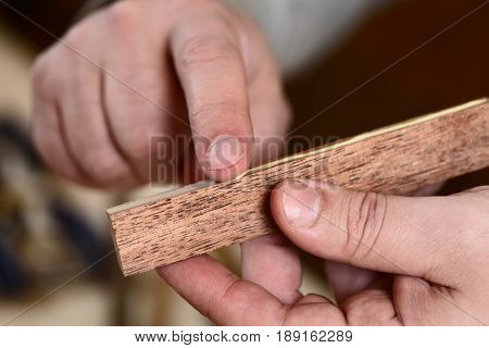 Carpenter applying glue on wooden plank with bare hands closeup
