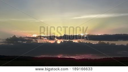 beautiful sky with shaft of sunlight and clouds during sunset and forest in spring