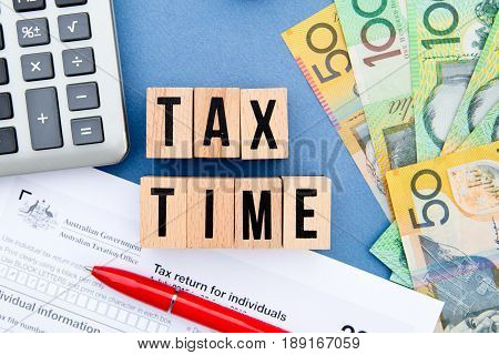 Tax Time - Australia - wooden letters with tax form, magnifying glass, money and calculator