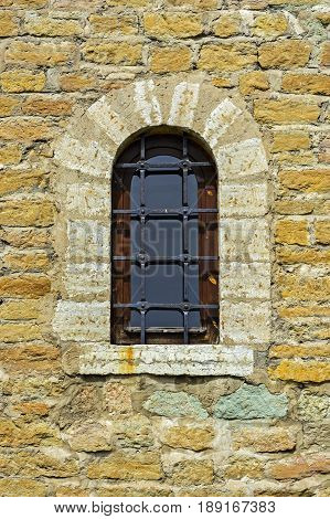 Window with an arch on the background of the wall of the old fortress of yellow limestone in the city of Narva.
