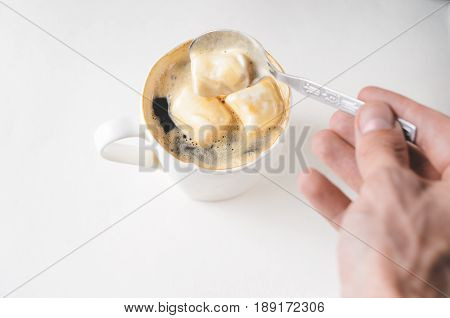 Mixing a spoon of coffee in a cup of marshmallows. White mug of hot drink with copy space background