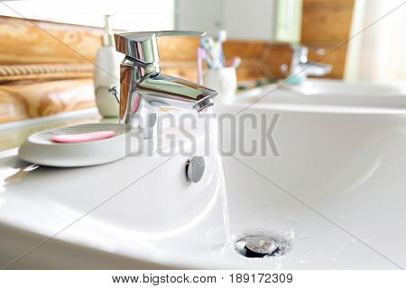 Working mixer tap in the bathroom closeup. water flows into the sink.
