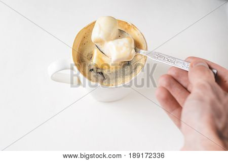 Mixing a spoon of coffee in a cup of marshmallows. White mug of hot drink with copy space background