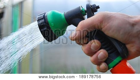 Watering the garden with a hose the hand of a person