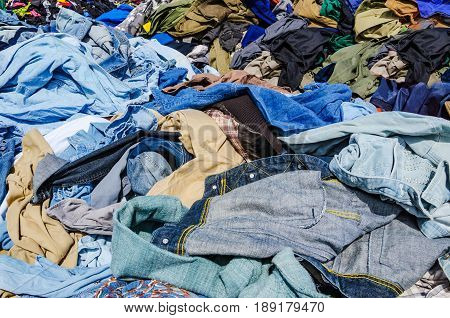 Heaps of clothing on the second hand market. Pile of second hand clothes at a garage sales
