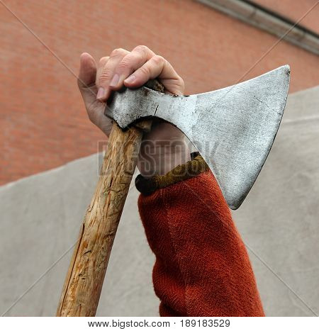 Hand of man leaning on old battle broadaxe. Axe before hand. Vikings widely used such weapon.