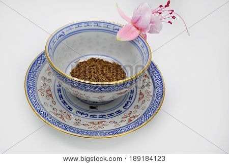 one pink flower fuchsia and black instant coffee in a small Cup and saucer