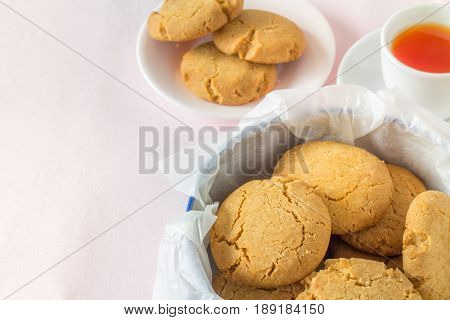 Homemade Gingernuts with Tea from Above on Pastel Pink Table Cloth with Copy Space