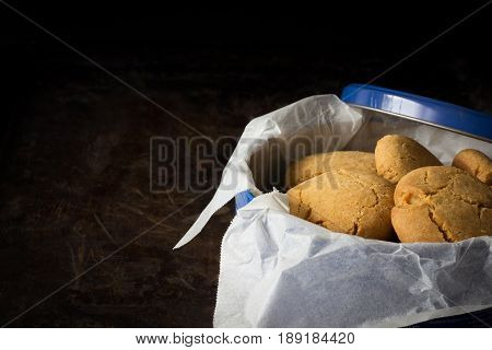 Gingernuts in a Blue Tin on a Dark Background Horizontal with Copy Space Left