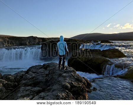 Woman standing in front of Godafoss waterfall in Northern Iceland