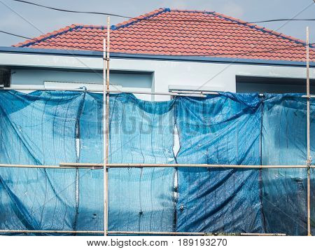 The house installs scaffold for construction with slan for preventing dust while under construction