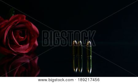 Bullet and red rose the black mirror background