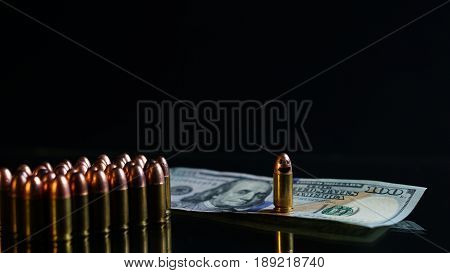 9mm bullet and US 100 dollars on the black mirror background.