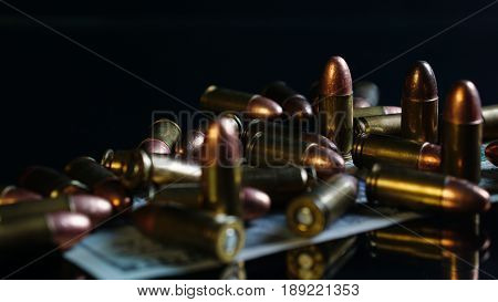 9mm bullets and US 100 dollars on the black mirror background.