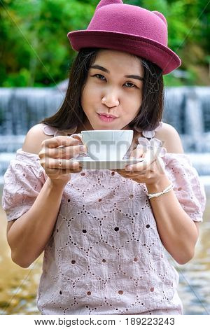 Asian woman relaxing on couch with coffee at water fall cafe.Close up