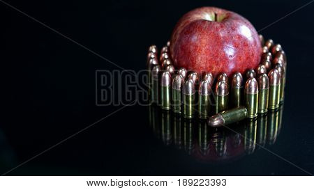 9mm bullets and a red apple on the black mirror background