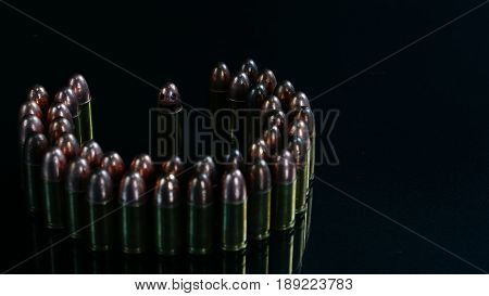 Smiling weapon. 9mm bullets on the black mirror background