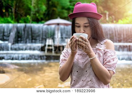 Asian woman relaxing on couch with coffee at water fall cafe.Close up