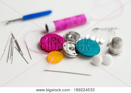 needlework and tailoring concept - sewing buttons, needles, pins and thread spool
