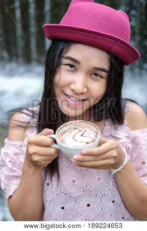Asian woman relaxing on couch with coffee at water fall cafe.Close up