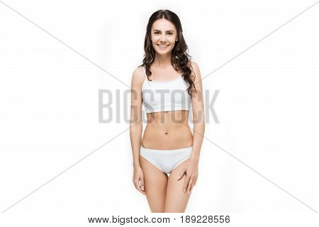 Attractive Smiling Woman Standing In White Underwear Isolated On White In Studio