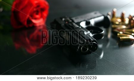 Black hand gun and bullets on the black mirror background.