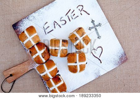 Easter - Hot Cross Buns
hot cross buns on floured wooden cutting board, with word Easter written in flour - with silver cross