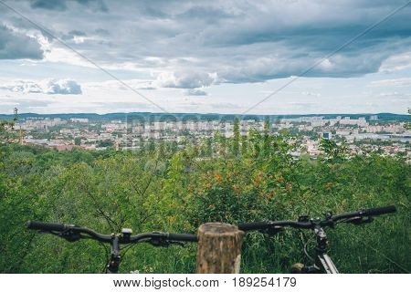 two bicycles stand on hill wth city view on background