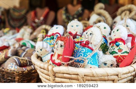 Colorful textile traditional female dolls as souvernirs sitting in basket, fair for tourists, on sale