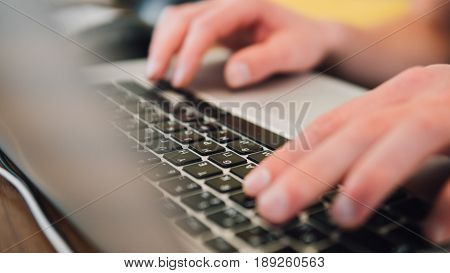 Work On The Laptop Keyboard Is A Close-up. Male Hands Of A Businessman Working Behind The Keyboard O