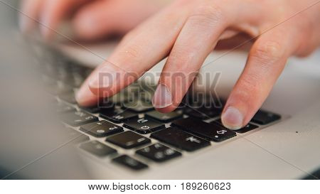Work On The Laptop Keyboard Is A Close-up. Male Hands Of A Businessman Working Behind The Keyboard O