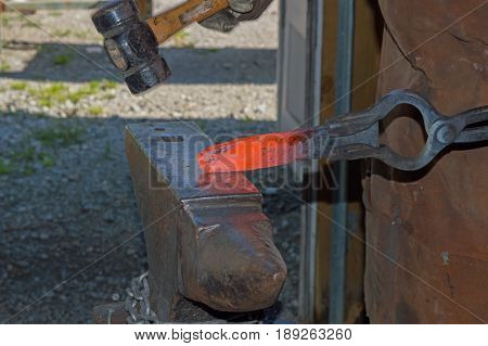 The skill of a seasoned bladesmith shapes hot metal into a knife blade