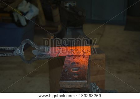 A billet of hot metal in the tongs of a bladesmith is about to be transformed into a useful knife