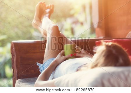 Girl drinking coffee / tea and enjoying the sunrise / sunset in garden.