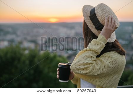 woman sit on the hill and lookin on sunset near city