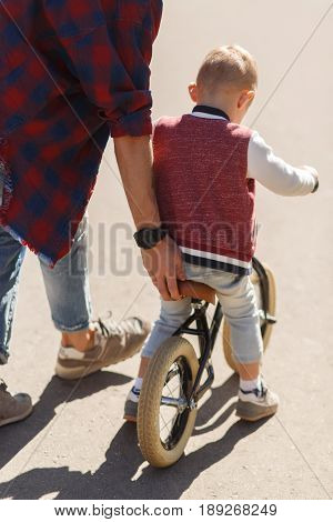 Dad teaches son to ride on bicycle in park during day