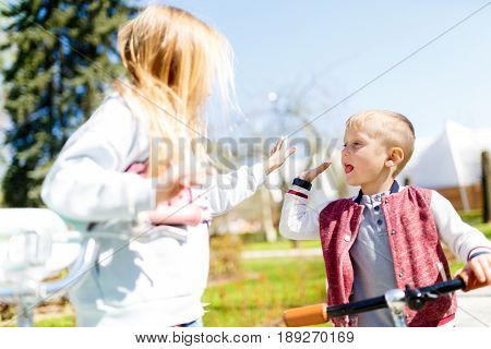 Boy with girl doing handshake in spring afternoon park