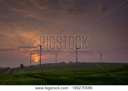 Silhouette of wind turbine generating electricity on sunset.