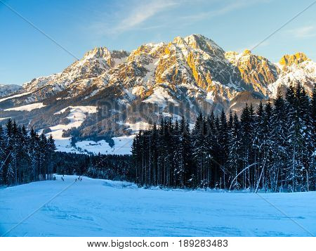 Downhill slope in Saalbach Hinterglemm Leogang winter resort, Tirol, Austria, Europe. Sunny morning with clear sky and illuminated mountain massive on the background.