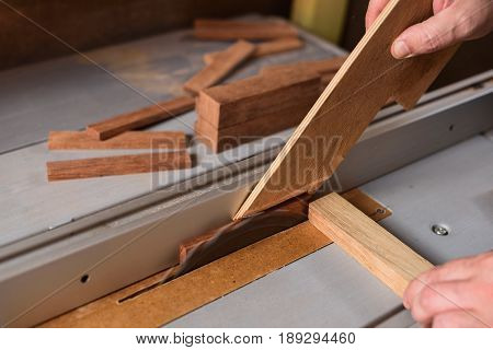 Carpenter sawing wood detail on circular saw hepling with stick for safety working