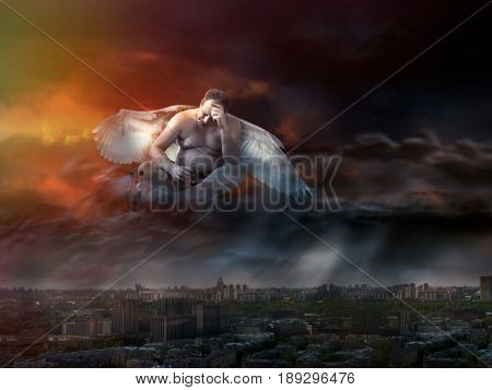Fat drunk man with angel wings in the sky. Sunset view from the heights of the city.