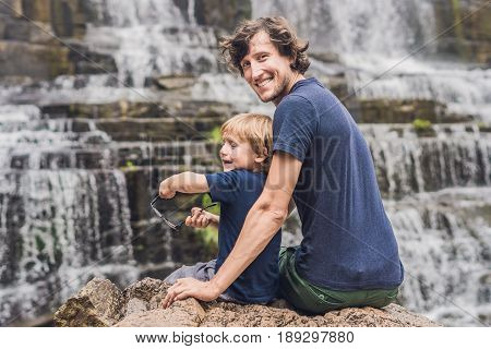Father And Son Hikers, Tourists On The Background Of Amazing Pongour Waterfall Is Famous And Most Be