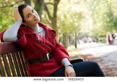 Caucasian หญิงสาวที่นั่งอยู่ในสวนบนม้าไม้