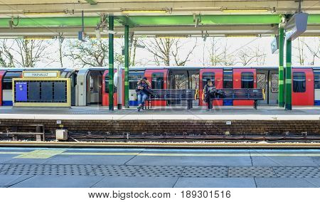 Hainault Ilford Essex England: March 3 2017: Platform at Hainault tube station with two passengers sitting reading.