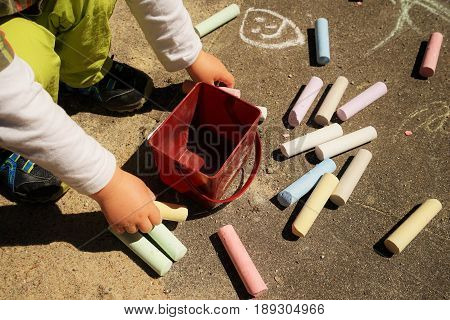 Children's hands and colorful chalk on a playground